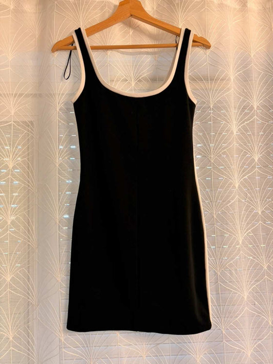 Robe noire sans manches avec bordure blanche, suspendue sur cintre en bois