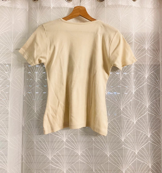 T-shirt beige uni en coton, suspendu sur cintre, idéal pour look casual et mode seconde main